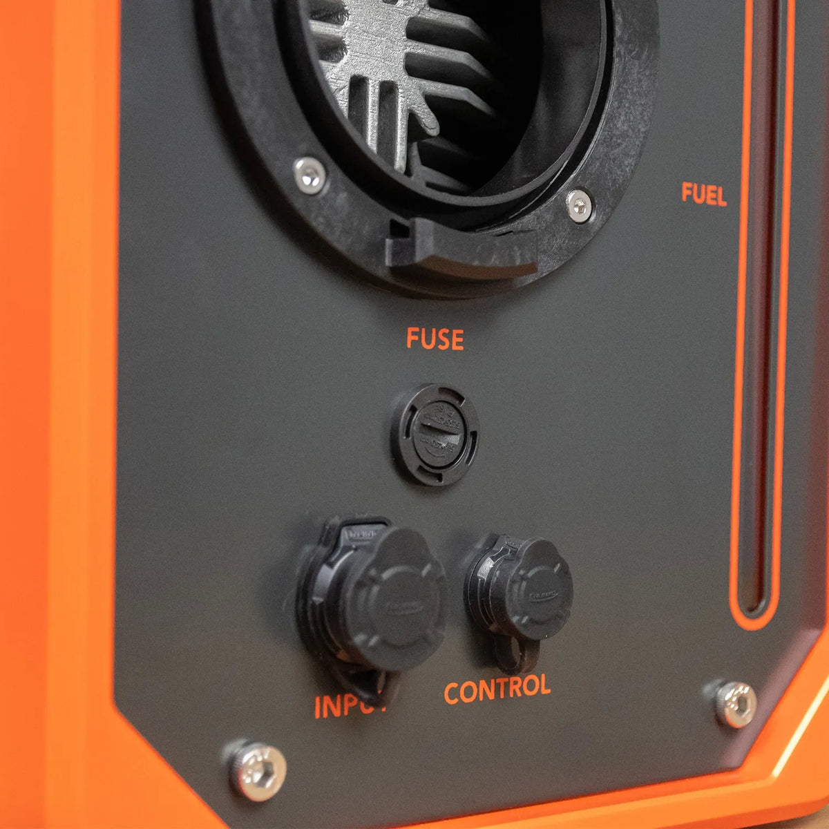 Close-up of the control panel of an orange and black generator, showing a fuel window, fuse socket, and two electrical outlets labeled INPUT and CONTROL.