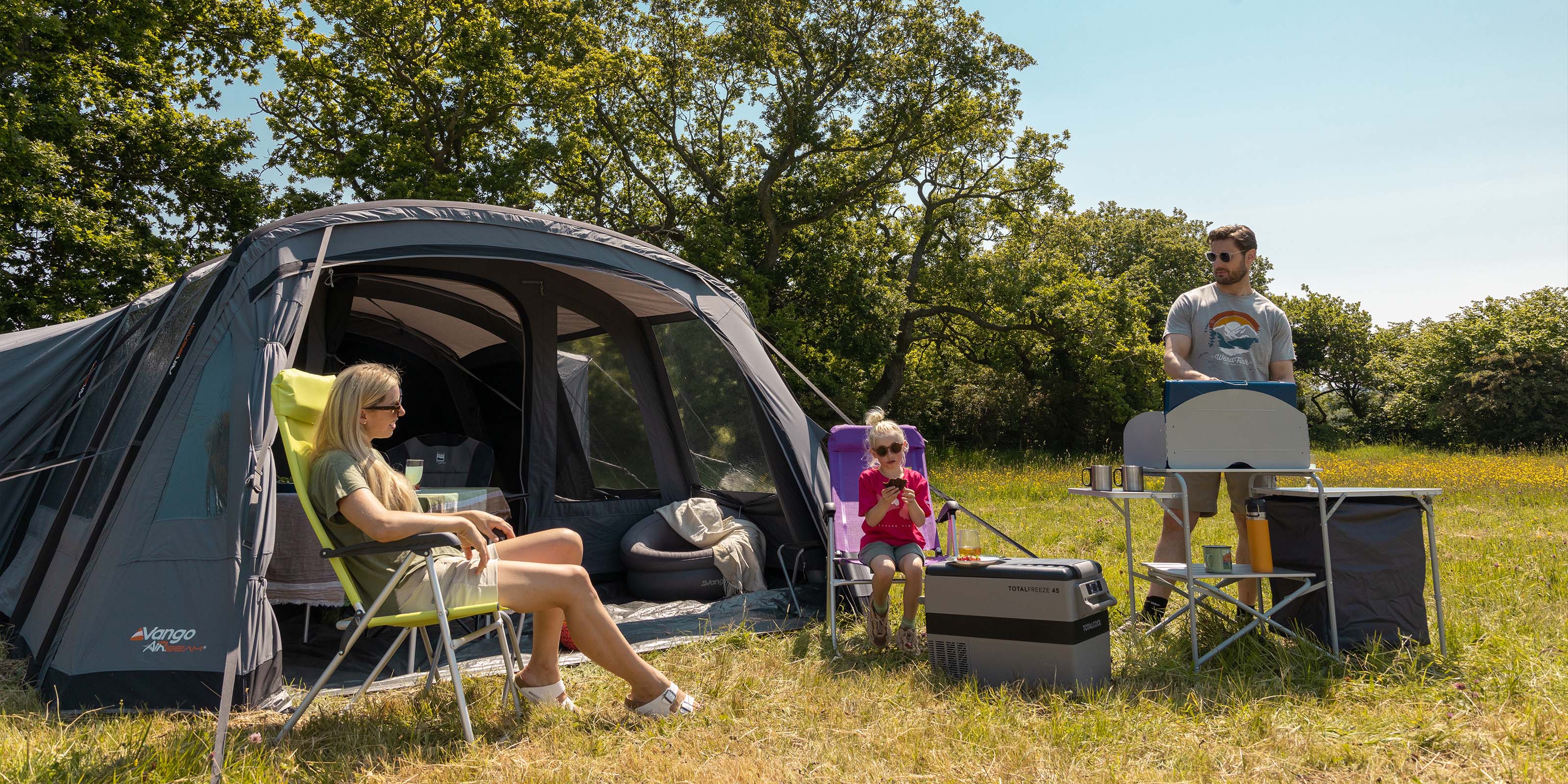 Image of a family camping who have their Totalfreeze 45 fridge freezer set up next to a barbeque