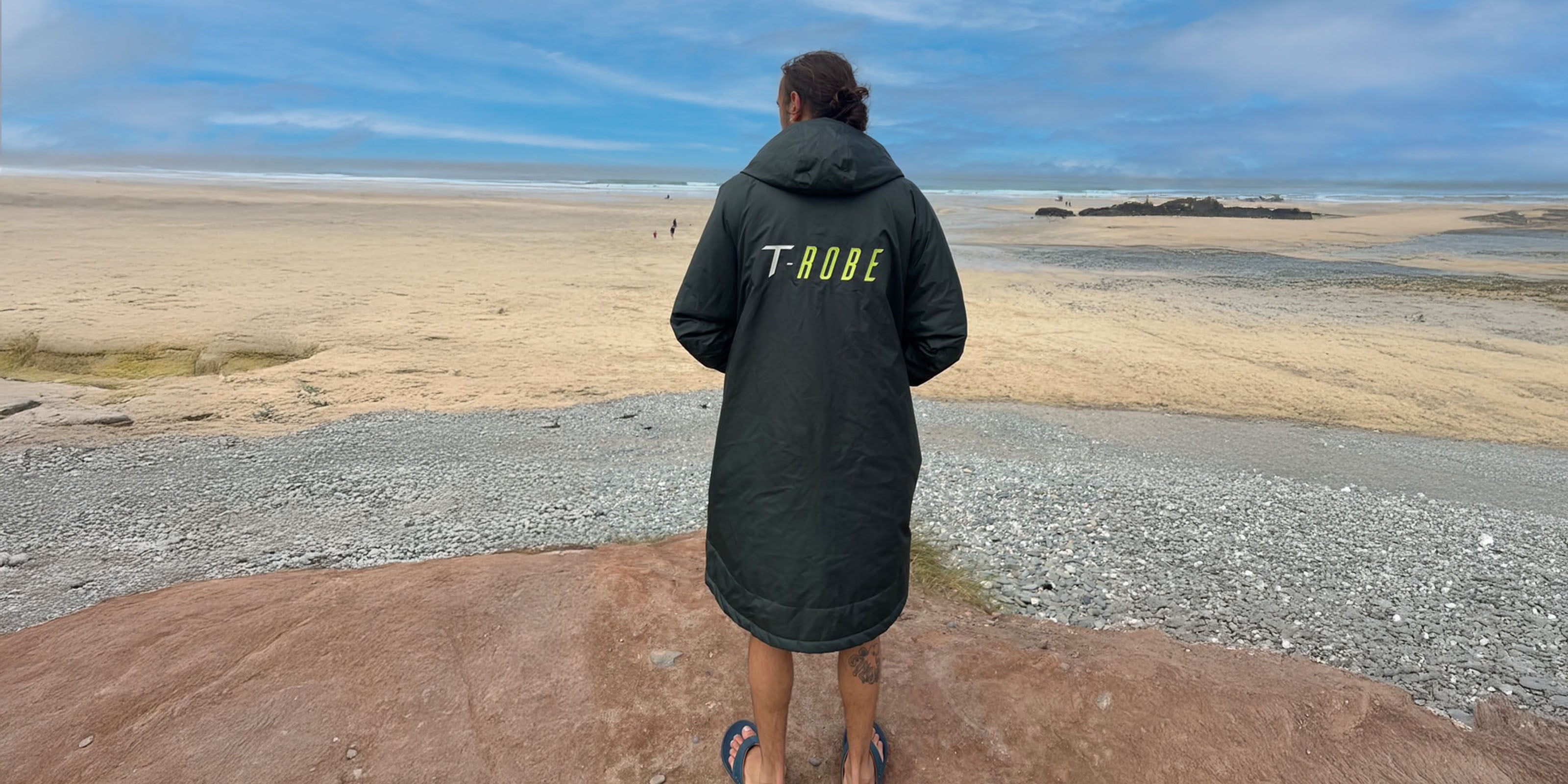 Image of a man wearing a beach changing robe by the ocean