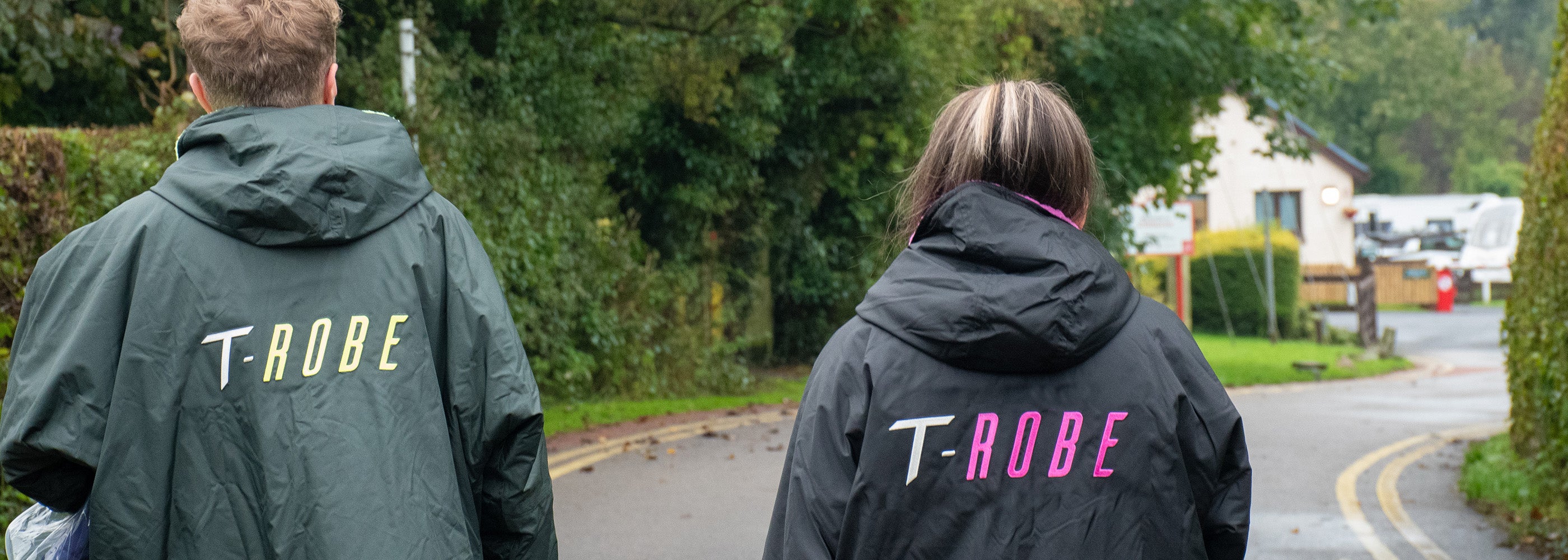 Image of a woman wearing a black and pink T-Robe alongside a man wearing a Deep green T-Robe 