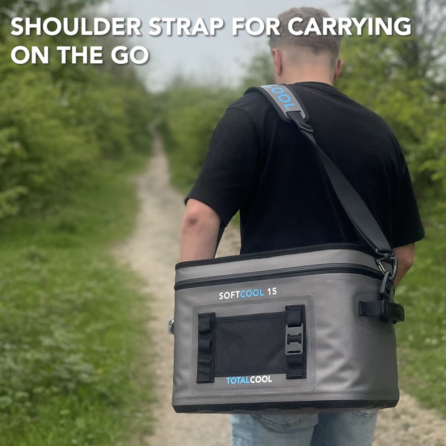 Image of the grey Softcool 15 coolbox being carried down a wooded path with the caption "Shoulder strap for carrying on the go"