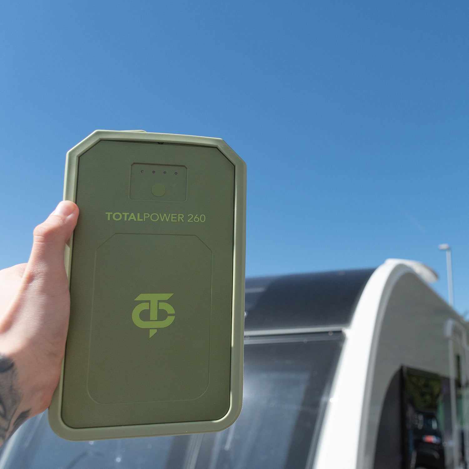 Green power bank with 'TOTALPOWER 260' branding held against a blue sky.