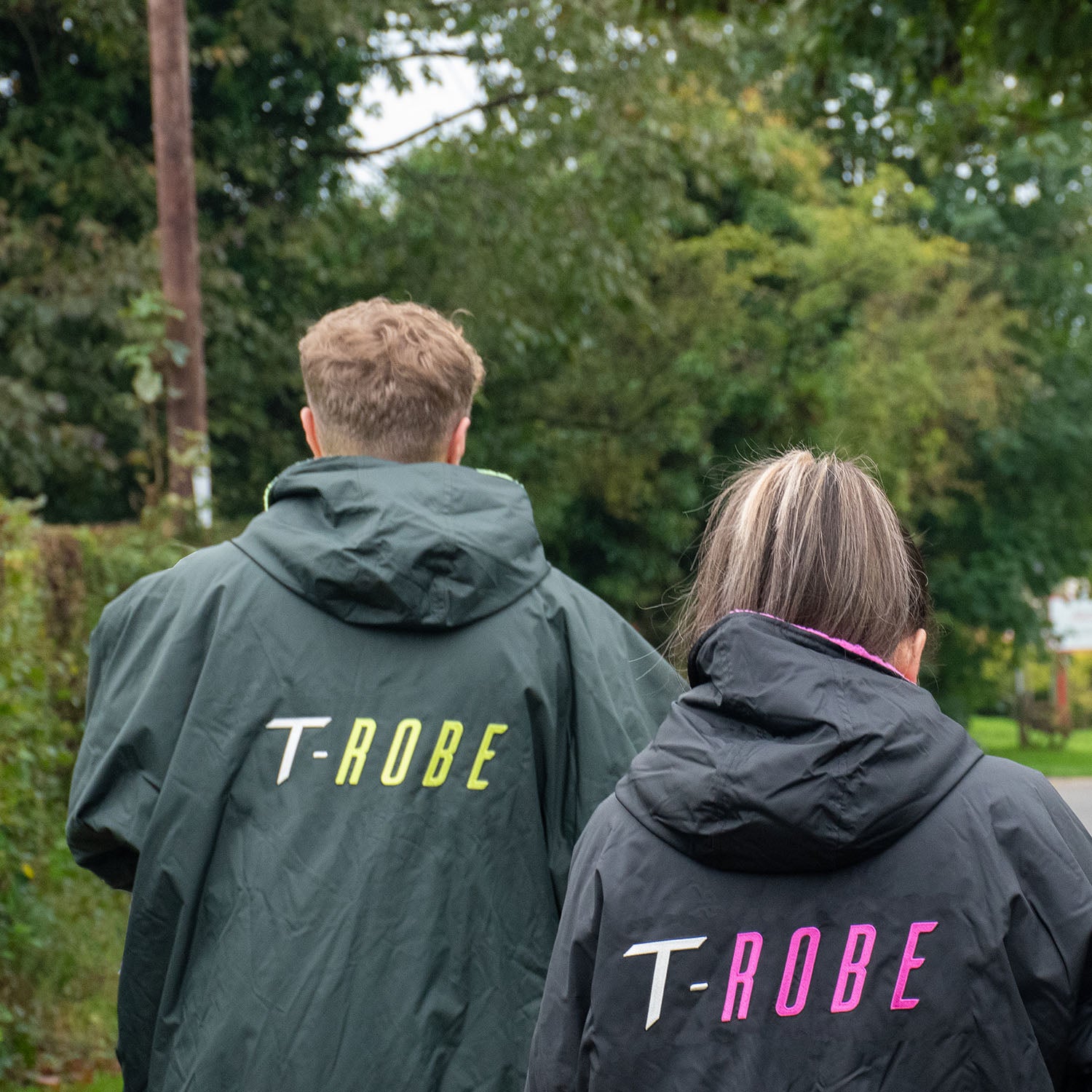 Two people wearing T-ROBE jackets with visible branding outdoors.