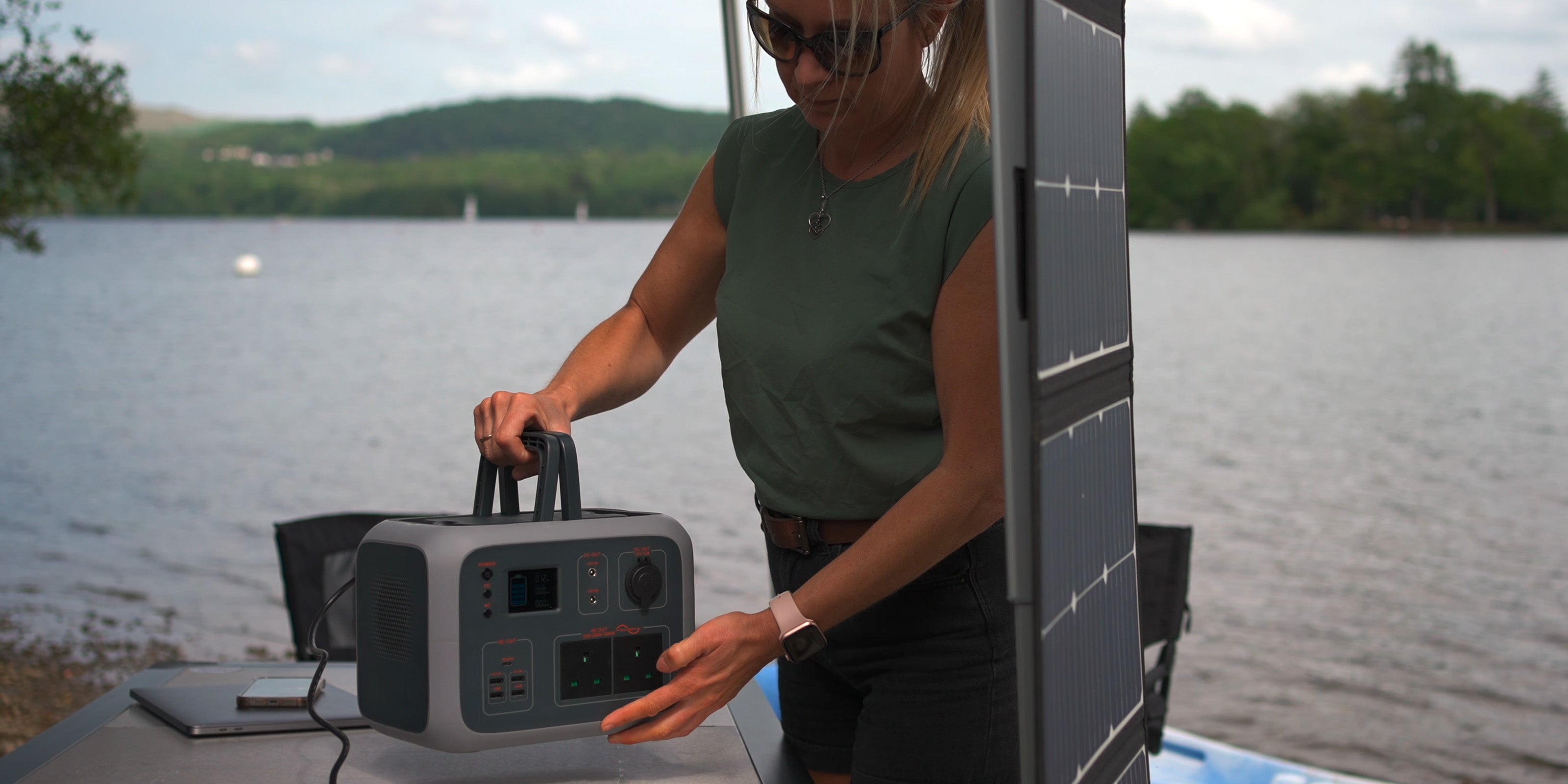 Image of a woman holding a TP500 power supply by the handles on a table outside of a campervan