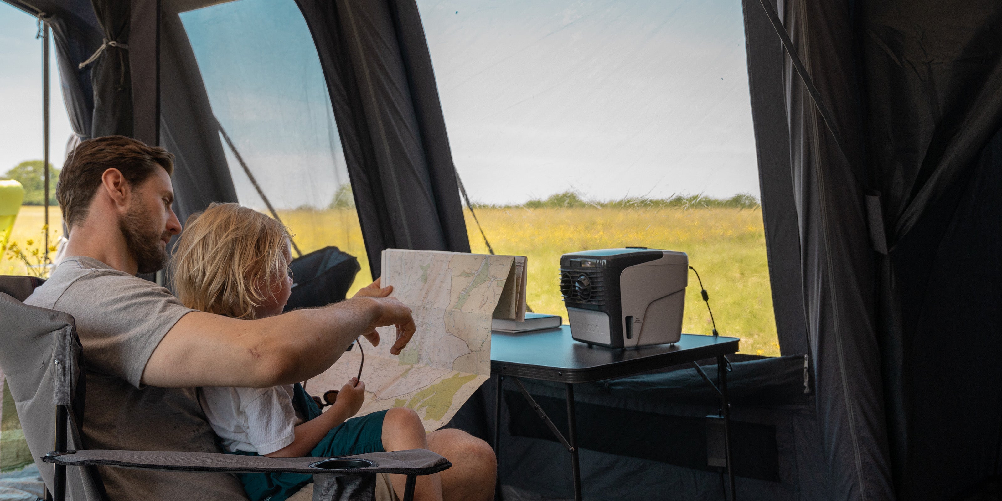 Image of a family sat in an awning with the TC3000 portable evaporative air cooler placed on a table