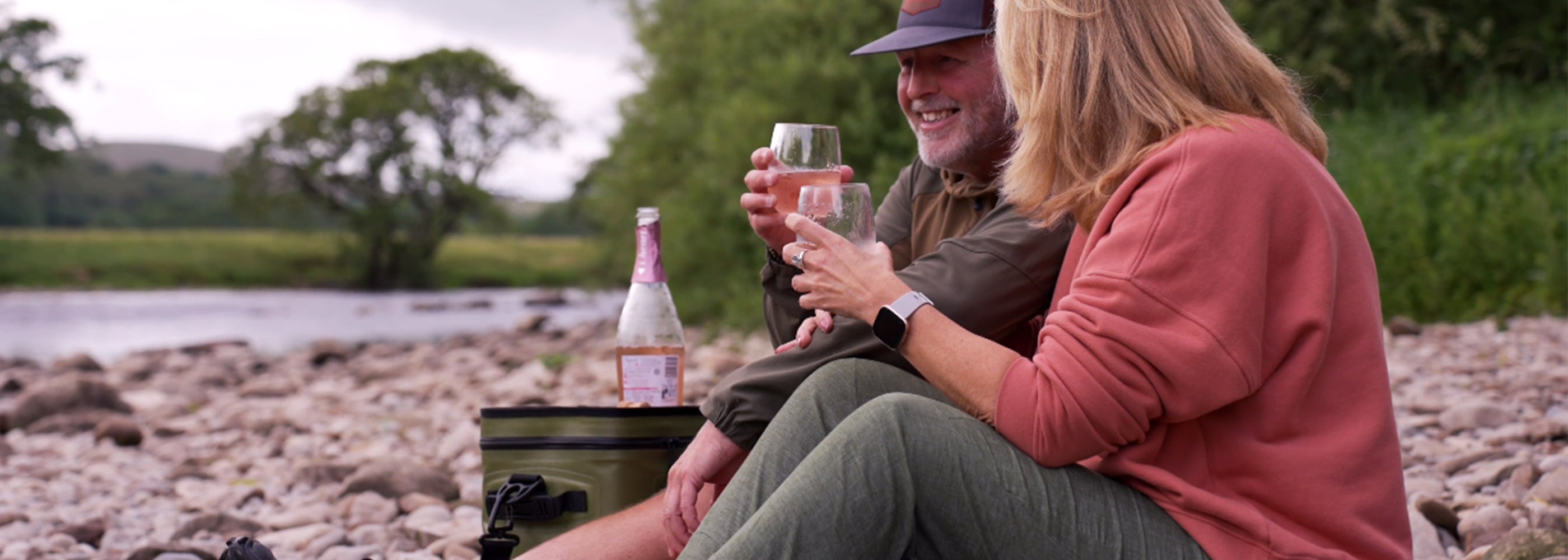 Image of a man and a woman enjoying a picnic outside utilising the green softcool coolbag